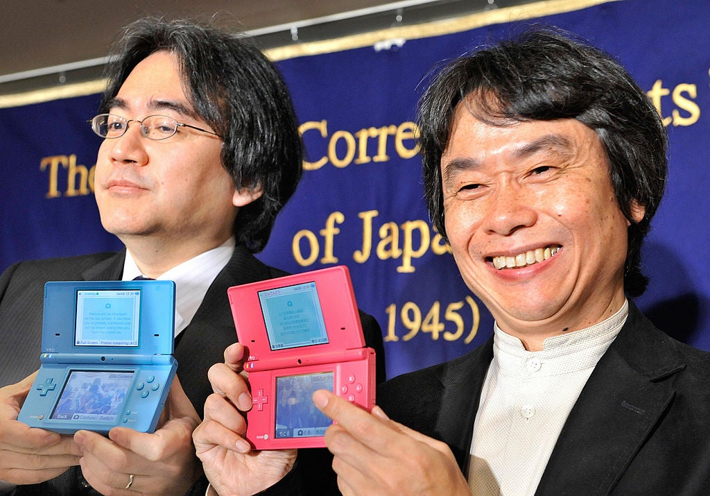 El presidente de Nintendo, Satoru Iwata (izq.), y el desarrollador de juegos Shigeru Miyamoto (derecha), conocido por su trabajo en Super Mario, Zelda y muchos de Los productos populares de Nintendo muestran una Nintendo DSi durante una conferencia de prensa en el Club de Corresponsales Extranjeros en Tokio el 9 de abril de 2009.